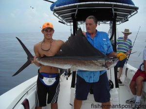 Bryce Umphress, from Wilmington, and Capt. Mike Jackson, of Live Line Charters, cradle a sailfish before releasing it. The sail fell for a ballyhoo under a blue/white Ilander in 170' off Wrightsville Beach