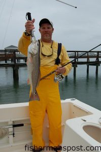 Capt. Mike Hoffman, of Corona Daze Charters out of Wilmington, with a mid-slot redfish. Hoffman hooked the red on a shrimp-tipped jig after skipping a cast under the dock in the background.