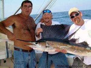 Tony Tew, Gary Sanders, and Tim Godfrey with a sailfish they hooked and released at the Horseshoe on a ballyhoo beneath a pink/white sea witch.
