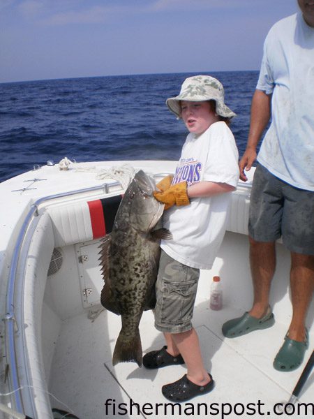 Will Schnieder (age 10), of Wilmington, hoists a high-teens gag grouper he hooked 25 miles off Carolina Beach on a live pogy while fishing with Chris Branco on the “Outalign.”