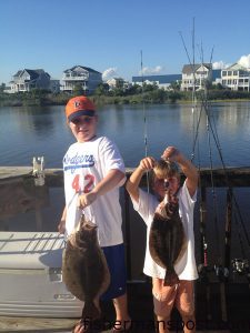 Caden Bolduc (age 9) and Fisher Broadwell (age 6) with a pair of flounder they hooked at some nearshore structure off Oak Island while fishing with uncle/father Andy Broadwell.