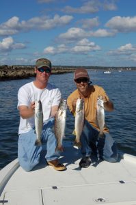 Capt. Kyle Hughes, of Speckulator Inshore Fishing Charters out of Ocean Isle, and Publisher Gary Hurley with a few of the specks and one gray trout they caught on a warm winter morning while floating live shrimp along the south rock wall in the Little River Inlet.