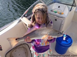 Charlie Francisco (age 6) with a slot red drum that struck cut shrimp near a Wrightsville Beach dock while she was fishing with her father Cameron.