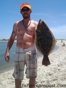 Joseph Aughtry with a 23" flounder that bit a live mud minnow at the point at Oak Island.