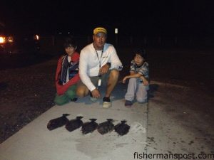 Capt. Damien James, of Elite Marine Charters out of the Topsail area, poses around midnight with Owen (left) and James (right) Hurley at the public boat ramp in Surf City. They gigged five flounder in some clean water near the inlet. No alligators were stabbed.