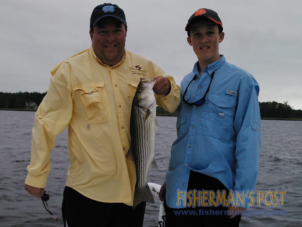 Lee and Garrison Peppers, of Raleigh, with a topwater striped bass they hooked near New Bern while fishing with Capt. Gary Dubiel of Spec Fever Guide Service.